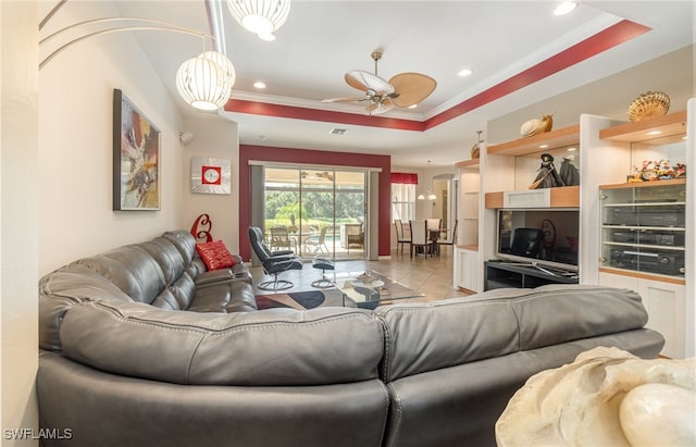 living room featuring ceiling fan, ornamental molding, a tray ceiling, and light tile patterned floors