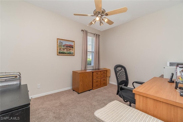 carpeted office space with a ceiling fan and baseboards