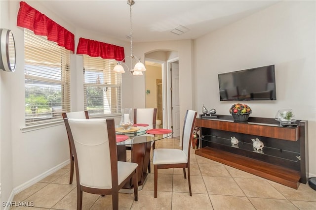 tiled dining space featuring baseboards, visible vents, arched walkways, and a notable chandelier