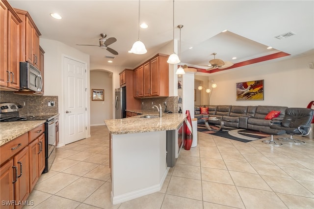 kitchen with appliances with stainless steel finishes, sink, ceiling fan, pendant lighting, and light stone counters