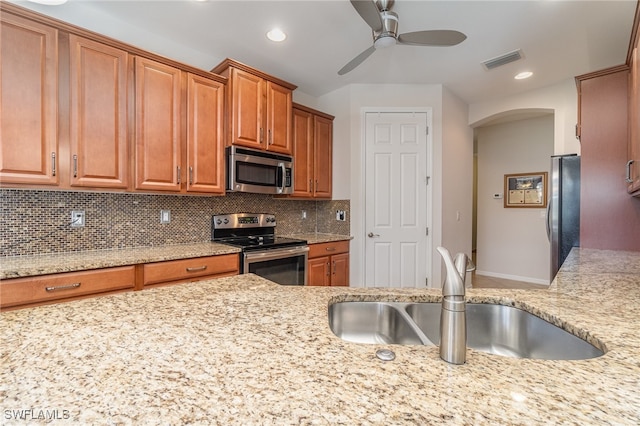 kitchen featuring sink, light stone countertops, ceiling fan, appliances with stainless steel finishes, and tasteful backsplash