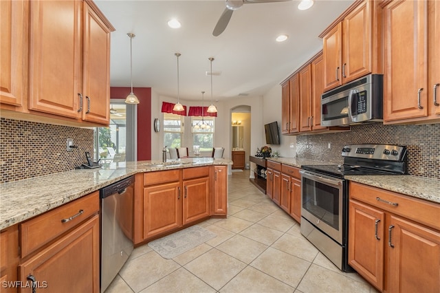 kitchen with hanging light fixtures, stainless steel appliances, light tile patterned floors, light stone counters, and ceiling fan