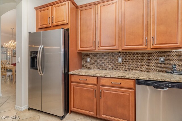 kitchen with appliances with stainless steel finishes, light stone counters, tasteful backsplash, and light tile patterned floors