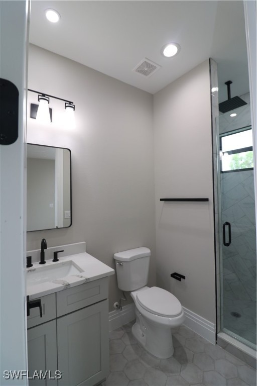 bathroom featuring tile patterned flooring, a shower with shower door, vanity, and toilet