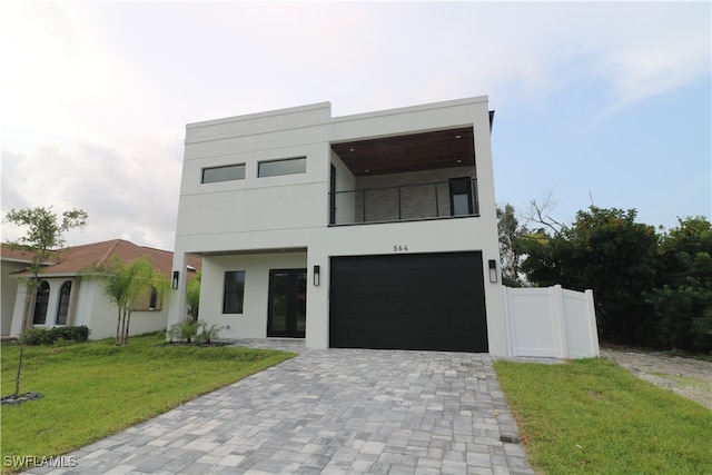 contemporary house with a balcony, a garage, and a front lawn