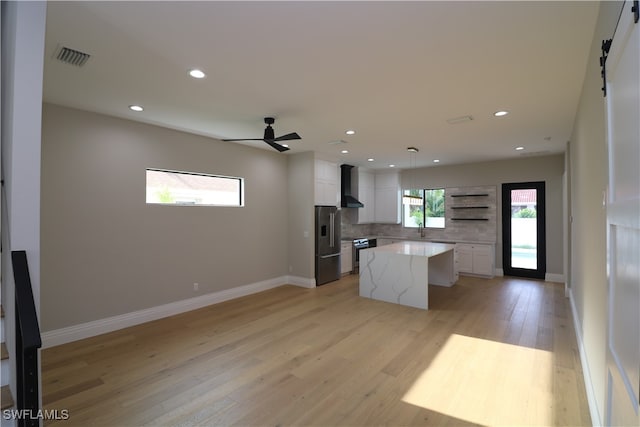 kitchen featuring light hardwood / wood-style floors, a kitchen island, backsplash, white cabinets, and appliances with stainless steel finishes