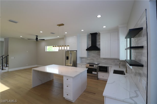 kitchen featuring pendant lighting, sink, a kitchen island, wall chimney exhaust hood, and stainless steel appliances