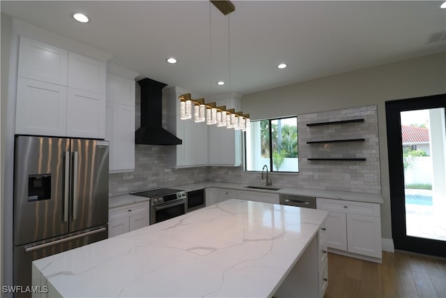 kitchen featuring sink, pendant lighting, wall chimney range hood, appliances with stainless steel finishes, and plenty of natural light