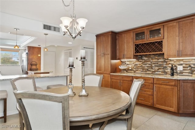 dining room with indoor bar, a tray ceiling, a chandelier, and light tile patterned floors