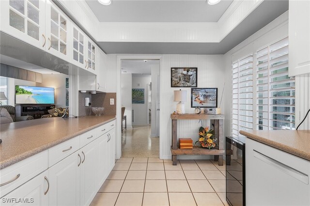 kitchen with light tile patterned flooring, backsplash, white cabinets, wine cooler, and ornamental molding