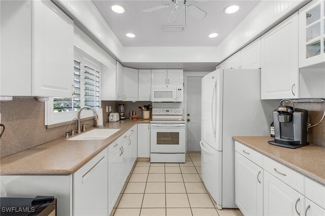 kitchen with white appliances, light tile patterned flooring, sink, and white cabinets