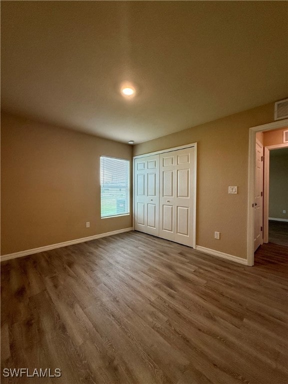 unfurnished bedroom featuring a closet and dark wood-type flooring