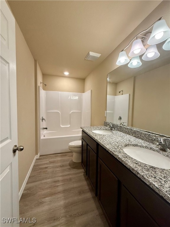 full bathroom featuring hardwood / wood-style floors, vanity, toilet, and shower / tub combination