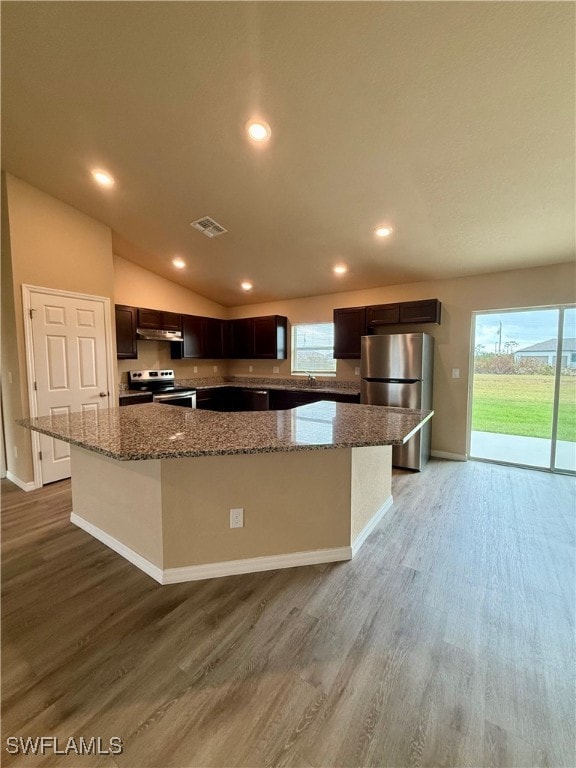 kitchen with hardwood / wood-style flooring, a kitchen island, appliances with stainless steel finishes, and vaulted ceiling