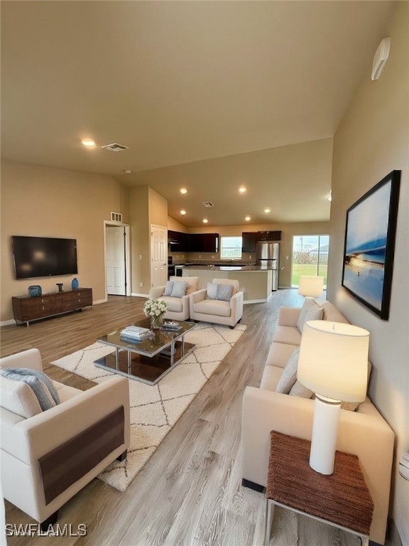 living room with light hardwood / wood-style floors and vaulted ceiling