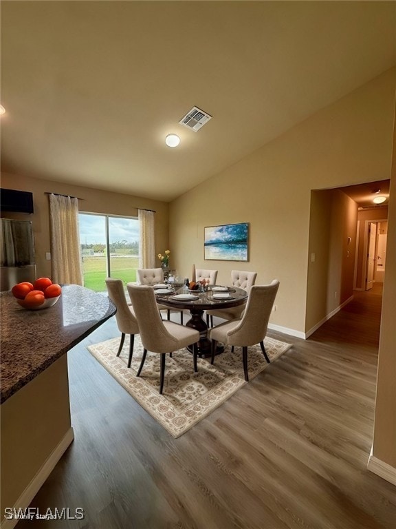 dining area with dark hardwood / wood-style floors and vaulted ceiling