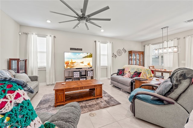 living room featuring light tile patterned floors, ceiling fan with notable chandelier, and plenty of natural light