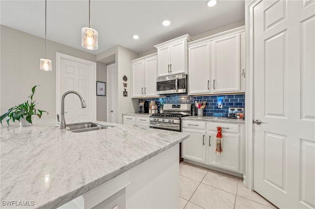 kitchen with light stone counters, stainless steel appliances, decorative light fixtures, and white cabinets