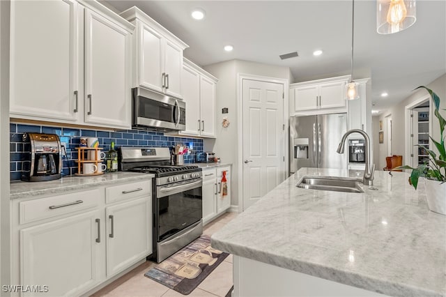 kitchen featuring appliances with stainless steel finishes, white cabinetry, sink, and hanging light fixtures