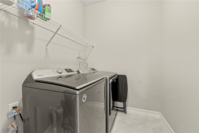 clothes washing area with light tile patterned flooring and washer and clothes dryer