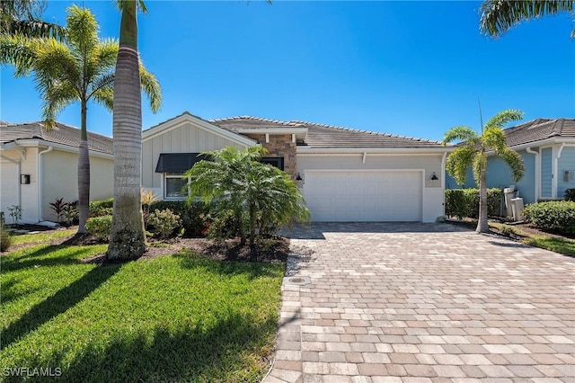 view of front of property with a front lawn, a garage, a tiled roof, decorative driveway, and board and batten siding