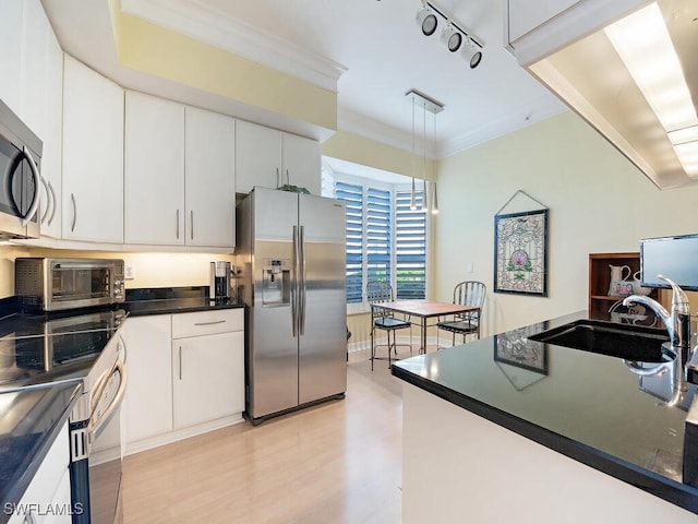 kitchen featuring stainless steel appliances, sink, pendant lighting, light wood-type flooring, and white cabinetry