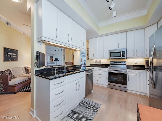 kitchen with appliances with stainless steel finishes, white cabinetry, and light hardwood / wood-style floors