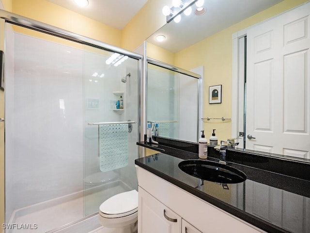 bathroom featuring toilet, vanity, and a shower with door