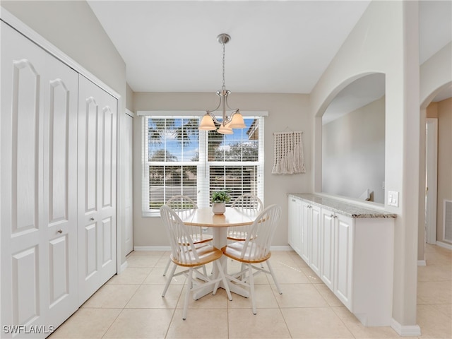 dining area with a chandelier, vaulted ceiling, and light tile patterned floors