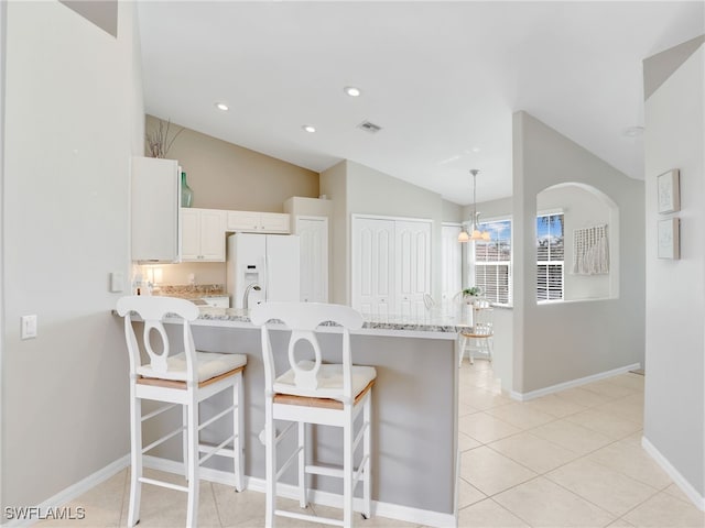 kitchen featuring a kitchen breakfast bar, kitchen peninsula, vaulted ceiling, white refrigerator with ice dispenser, and white cabinetry