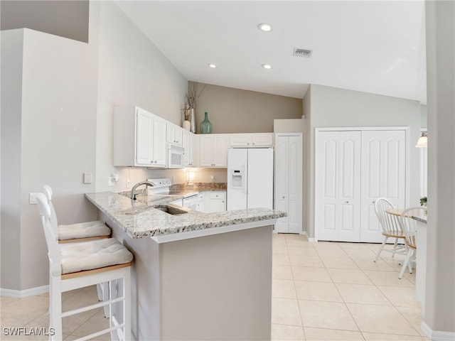 kitchen featuring a breakfast bar area, white cabinetry, vaulted ceiling, sink, and white appliances