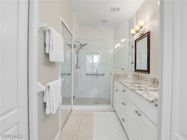 bathroom with a shower with door, vanity, and tile patterned floors