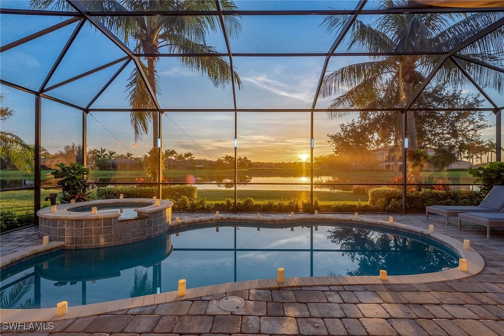 pool at dusk featuring an in ground hot tub, a patio area, and glass enclosure