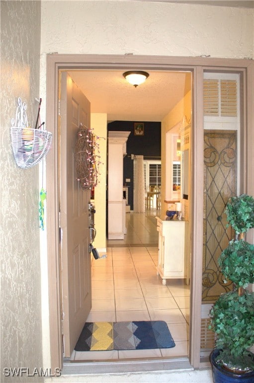 hall with a textured ceiling and light tile patterned flooring