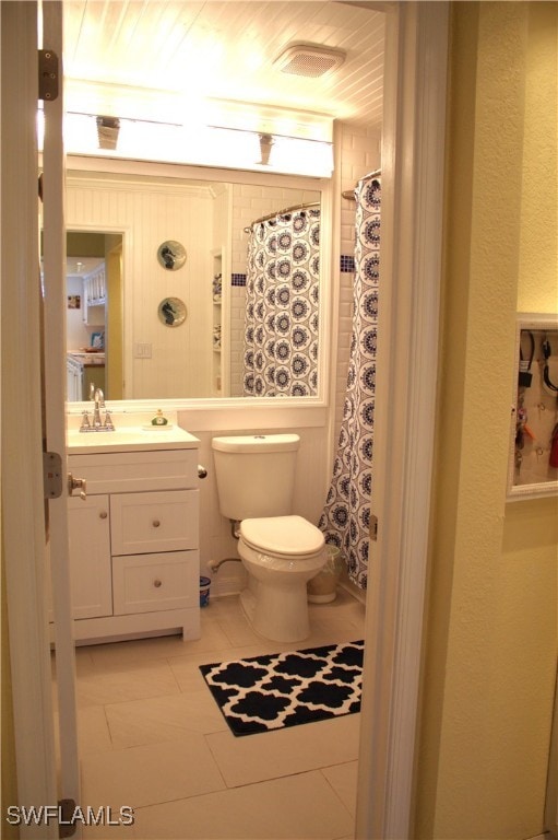 bathroom featuring toilet, vanity, a shower with shower curtain, and tile patterned flooring