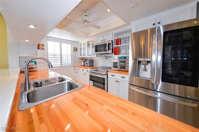 kitchen featuring stainless steel appliances, sink, wooden counters, and white cabinets