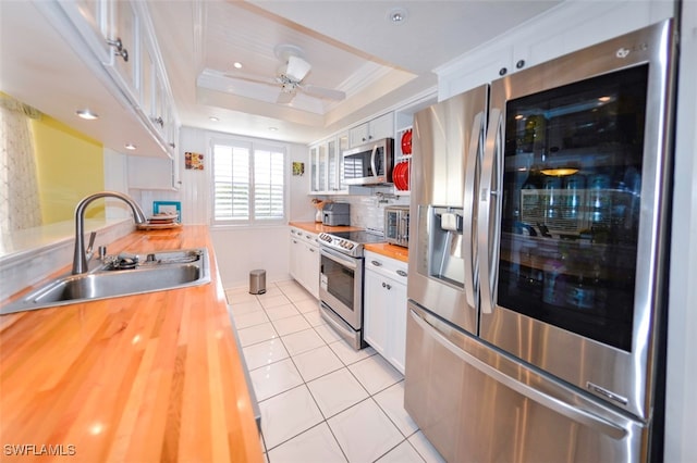 kitchen featuring white cabinetry, sink, butcher block counters, and appliances with stainless steel finishes