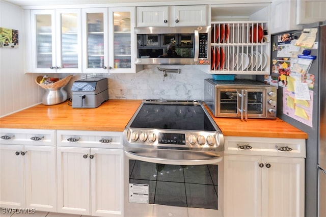 kitchen with backsplash, appliances with stainless steel finishes, wooden counters, and white cabinets