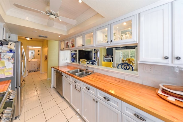 kitchen featuring butcher block countertops, sink, stainless steel appliances, a tray ceiling, and white cabinets