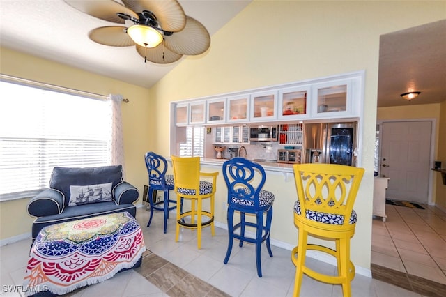 interior space featuring vaulted ceiling, sink, light tile patterned flooring, and ceiling fan