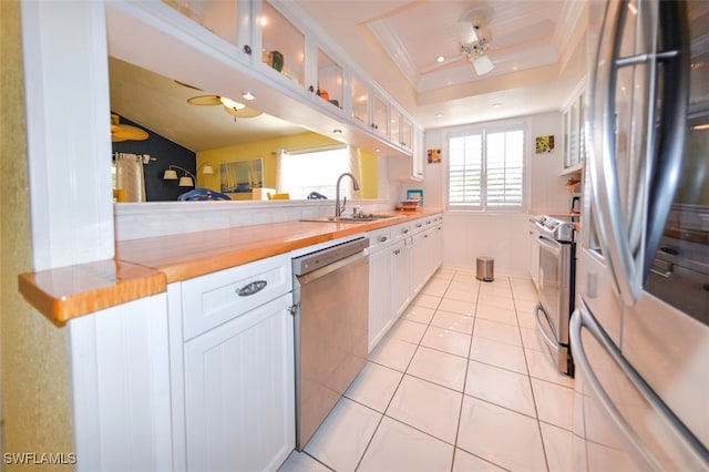 kitchen featuring stainless steel appliances, sink, butcher block countertops, and white cabinets