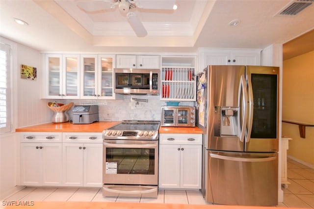 kitchen featuring light tile patterned floors, a tray ceiling, stainless steel appliances, and white cabinets