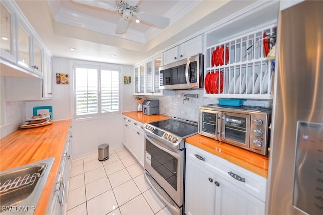 kitchen featuring wood counters, a raised ceiling, white cabinetry, sink, and stainless steel appliances