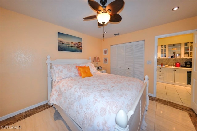 bedroom featuring light tile patterned flooring, wine cooler, ceiling fan, and a closet