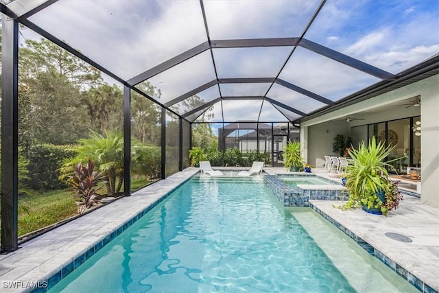 view of swimming pool featuring an in ground hot tub, pool water feature, glass enclosure, and a patio area