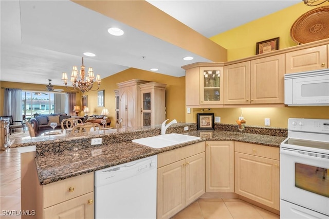 kitchen with kitchen peninsula, white appliances, dark stone countertops, and sink