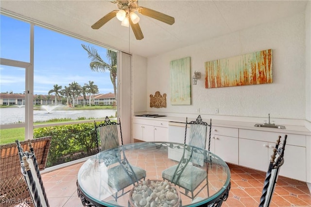 dining space featuring a water view, light tile patterned floors, and sink