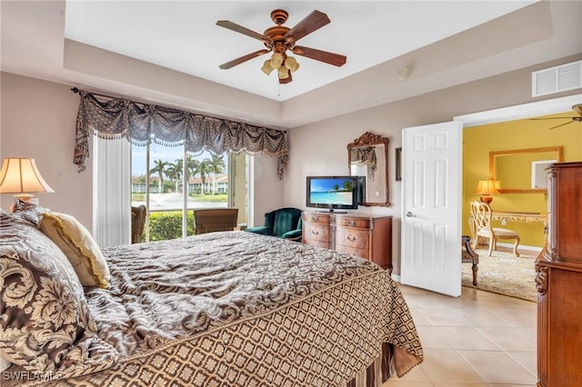 bedroom with ceiling fan, a raised ceiling, light tile patterned floors, and access to outside