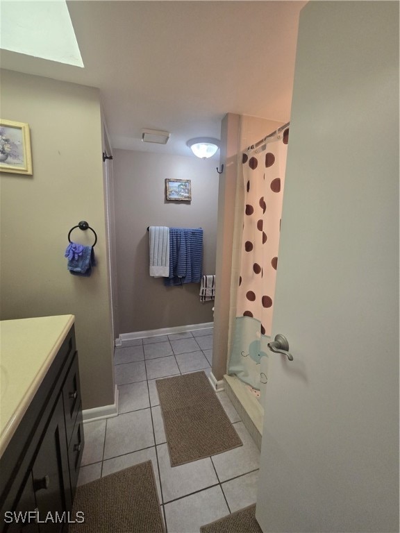 bathroom with a skylight, a shower with curtain, vanity, and tile patterned flooring