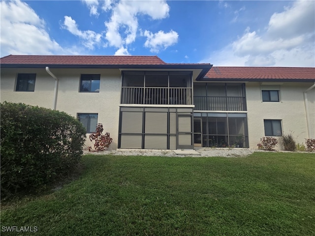 rear view of property with a sunroom and a lawn